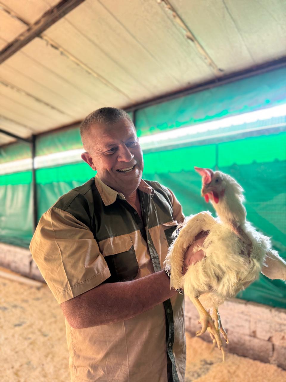 Team member holding a chicken at Ubuntu Harvest Africa