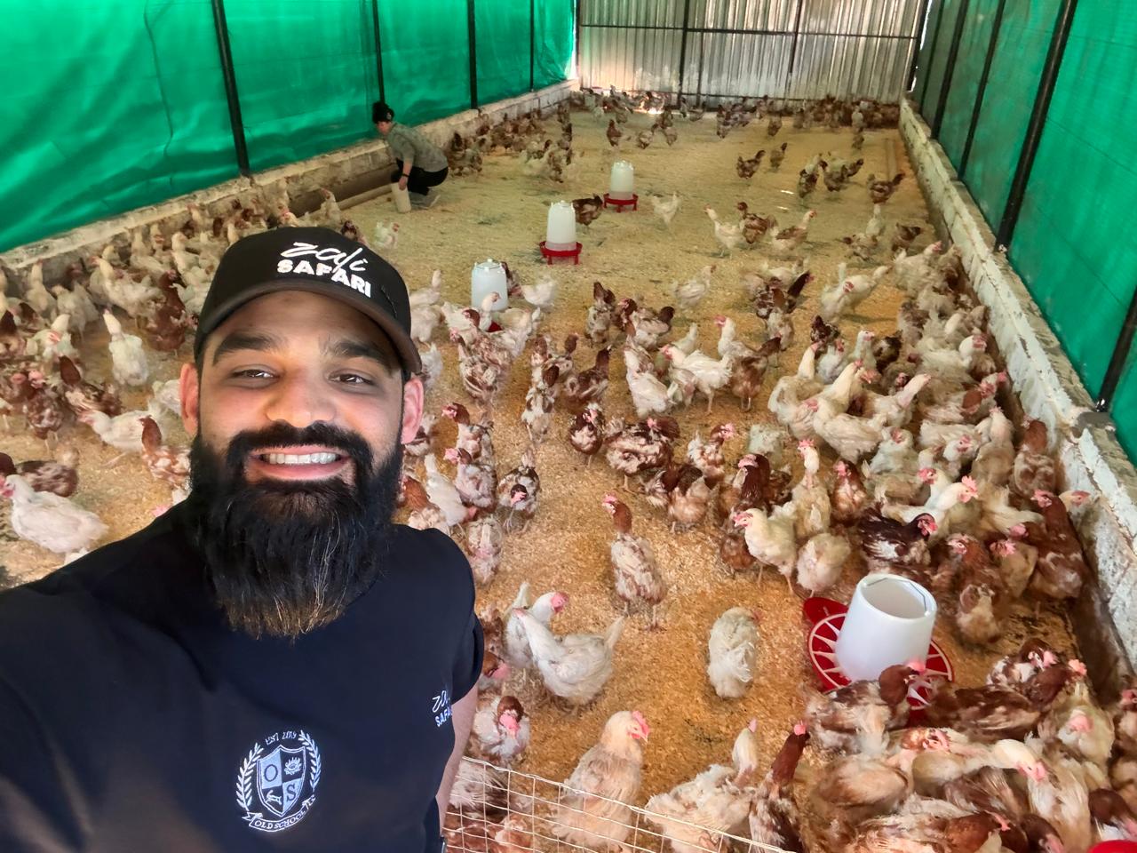 Team member with chickens inside the Ubuntu Harvest Africa farm house